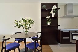 Dining table and blue chairs open to kitchen