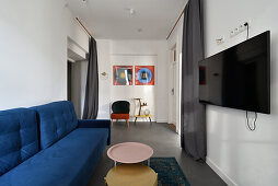 Modern living room with blue sofa, TV on wall and coffee table