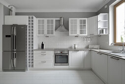 Modern kitchen with stainless steel appliances and white wall tiles