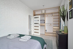 Bright bedroom with shelved wardrobe and white brick wall