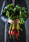 Man holding fresh beetroot with leaves