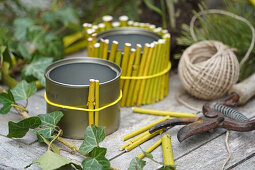 DIY bamboo vase, box made of yellow branches, snowdrop (Galanthus) and secateurs on garden table