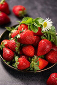 Fresh strawberries in a metal bowl on a wooden background