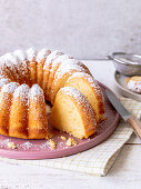 Quark bundt cake on a pink plate dusted with icing sugar