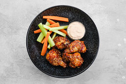 Chicken drumsticks teriyaki with celery and carrot sticks and dip