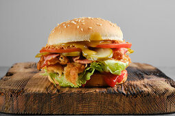 Chicken burger with bacon, gherkins and tomato