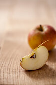 Whole apple and apple wedge on wooden table