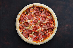 Pizza with ham, bacon, sausage, tomato and mushrooms