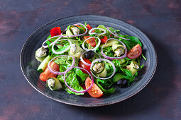 Courgettes stuffed with feta on a bed of lettuce with tomatoes, cucumber and olives