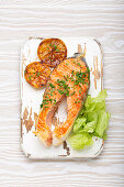 Grilled salmon steak with lemon slices and green salad