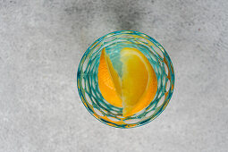 Water glass with orange slices and ice cubes