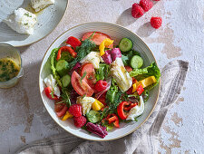 Summer mozzarella vegetable salad with tomatoes, cucumber and raspberries