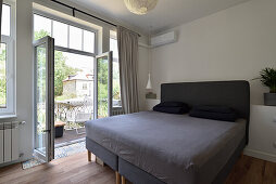 Modern bedroom with balcony and large double bed in grey tones