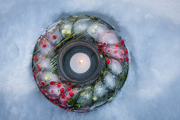 Gefrorener Kranz mit Stechpalme (Ilex) und Mistel im Schnee als Weihnachtsdekoration