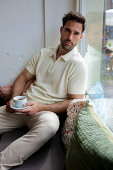 Man in cream polo shirt enjoys espresso