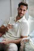 Man in cream polo shirt enjoys espresso