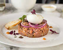 Steak Tartare mit Zwiebelringen und pochiertem Ei