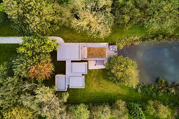 Aerial view of a house with green roof and pond, UK