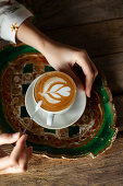 Cappuccino with latte art on traditional tray