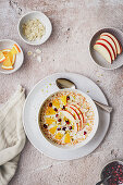 Porridge with apple slices, orange, pomegranate seeds and almonds