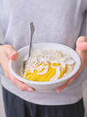 Overnight-Oats mit frisch geschnittenen Mangoscheiben und Kokosflocken