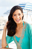 Young woman in turquoise embroidered tunic on the beach