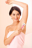 Young woman shaving her armpit hair