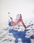 Man jumping in sand playing beach ball, Sylt, North Sea, Germany