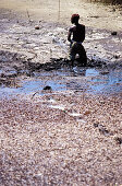 African boy digging hole, people at work