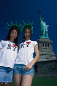Two smiling girls in front of the Statue of Liberty, Liberty Island, New York USA, America
