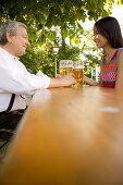 Older Bavarian man and asian woman sitting in beer garden, Munich, Bavaria