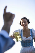 Waitress serving beer stein to guest in beer garden, Munich, Bavaria