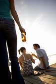 Young people drinking beer on boardwalk and looking at sunset, Munich, Bavaria