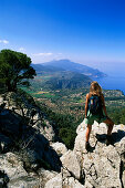 Woman standing on bridleway of archduke, view to Calla de Valldemossa, Serra de Tramuntana, Majorca, Spain