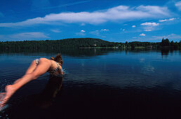 Frau macht ein Kopfsprung in den See Sommen, Östl. Tranas, Östergotland, Schweden