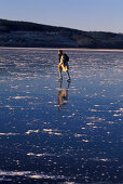 Woman skating on ice, lake in Vastergotland, Sweden