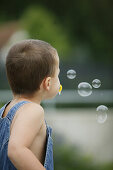 Boy making soap-bubbles, people