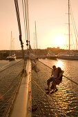 Paar sitz im Netzt, Bugsprietnetz, Star Flyer, Sonnenuntergang über Rhodos Hafen, Rhodos, Dodekanes, Griechenland
