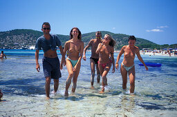 Eine Gruppe junge Männer und Frauen am Strand, Sa Trincha, Platja de ses Salines, Ibiza, Balearen, Spanien