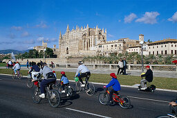 A group of cyclists, Cathedral of Santa Maria of Palma, Palma Cathedral, Cathedral La Seu in the background, Palma de Mallorca, Mallorca, Spain