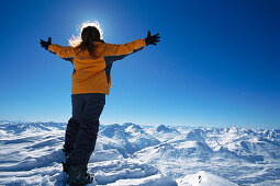 Woman enjoys view on top of Valluga, arms outstreched, St. Anton at Arlberg, Tyrol, Austria
