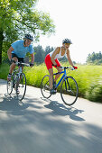 Young couple riding fitness bikes, Bavaria, Germany