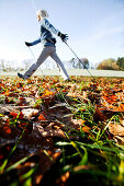 Young woman Nordic Walking through Autumn leaves, Voralpenland, Oberambach, Lake Starnberg, Bavaria, Germany