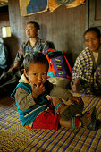 Burmese child sitting on floor with family, Burma, Myanmar