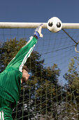 Young goalkeeper jumping for ball