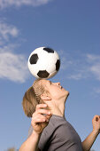 Young soccer player juggling ball on his head