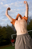 Young male soccer player jubilating, lifting t-shirt