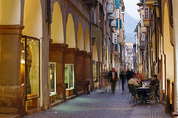 Menschen in einer Gasse mit Läden in der Abenddämmerung, Laubengasse, Bozen, Südtirol, Italien, Europa
