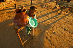 Child drinks water from terracotta pot, Junge trinkt Wasser aus Tontopf, Wasserbehaelter aus Ton, typisch