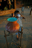 Child drinks water from terracotta pot, Kind trinkt Wasser aus dem Tontopf, Tonkrug, diese Wasserbehaelter stehen ueberall in Burma